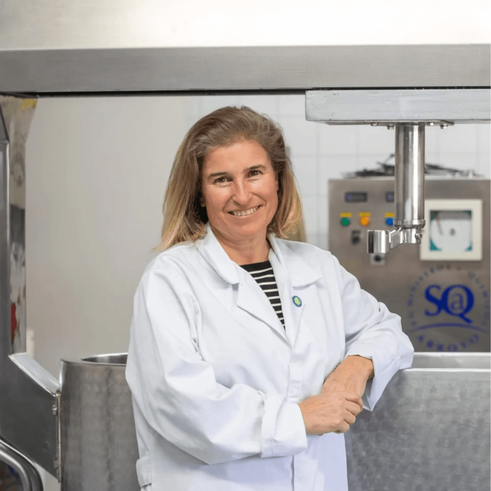 Mujer sonriente en laboratorio con uniforme blanco.