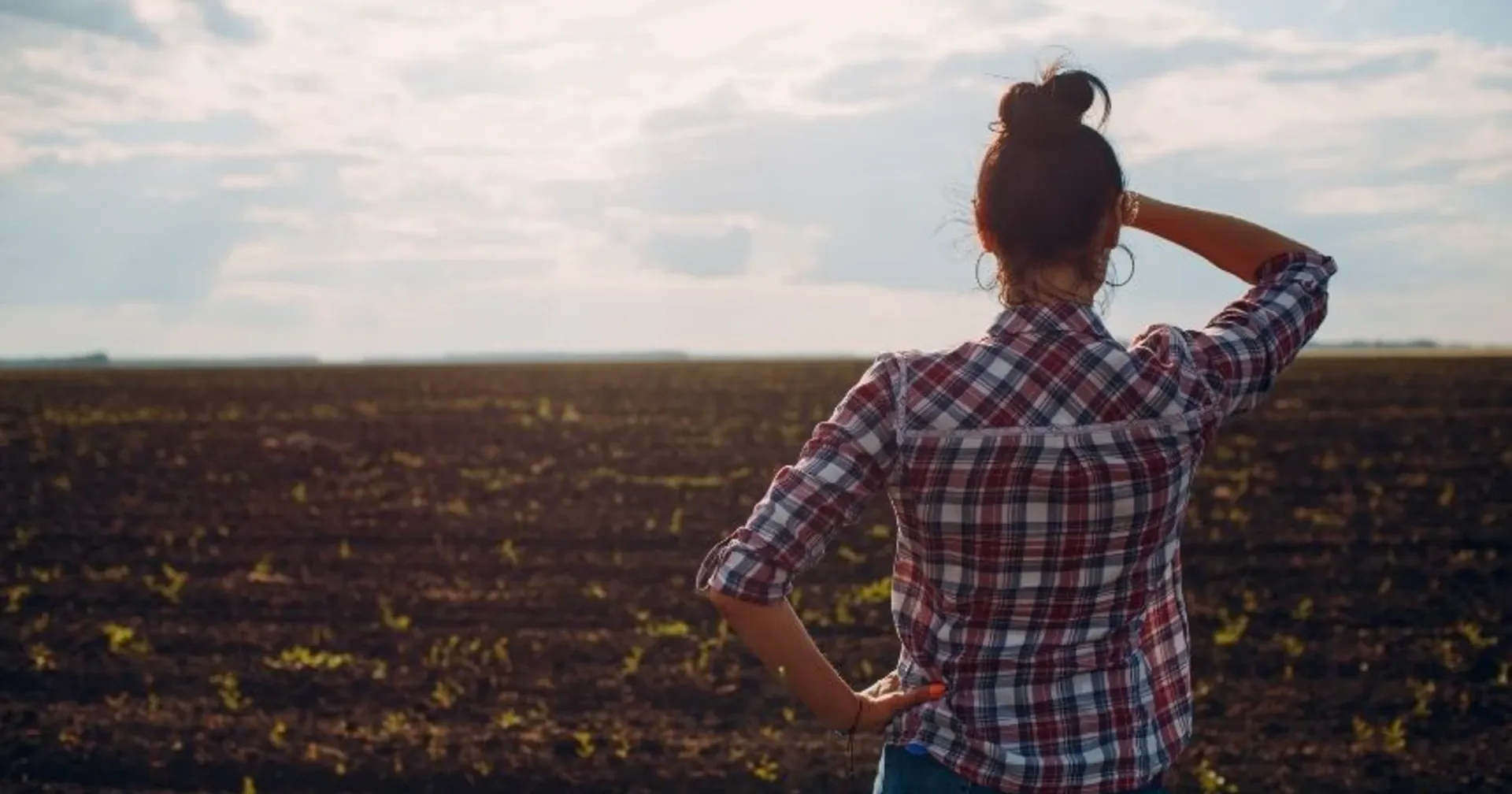 Emprender en el campo: qué está pasando en España y en Europa Una mujer con cabello en rollos, con una camisa de cuadros, en un campo de cultivo.