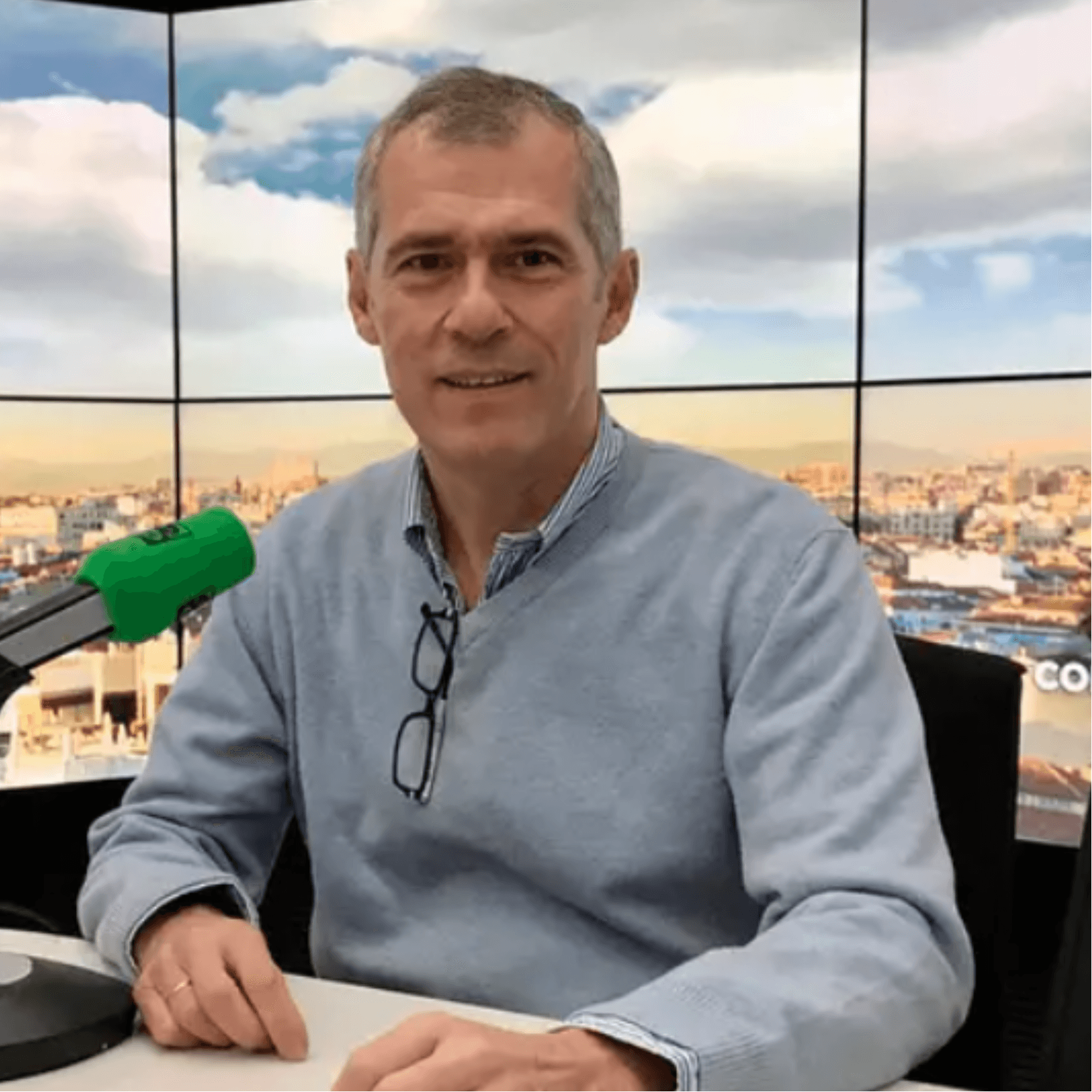 Hombre sonriendo en un estudio de televisión con vista a la ciudad. Hombre sonriendo en un estudio de televisión con vista a la ciudad.
