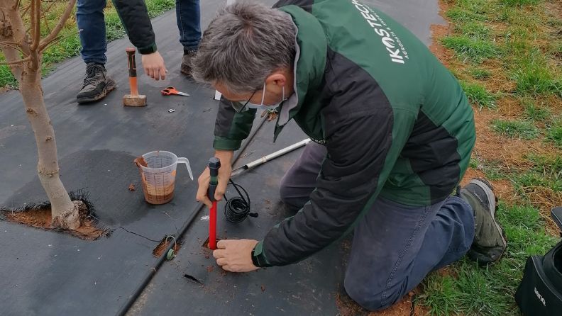 Hombre ensamblando tubo rojo en la tierra.
