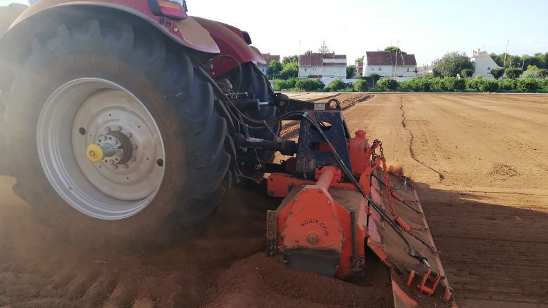 Tractor trabajando en un terreno con una herramienta agrícola.