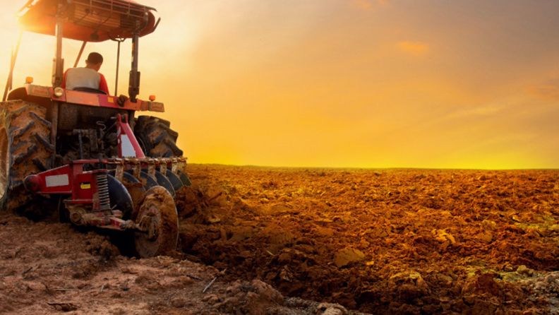 Tractor en un campo agrícola al amanecer