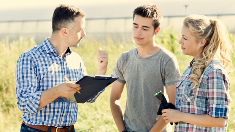 Profesor explicando a dos alumnos materias relacionadas con el campo agrario