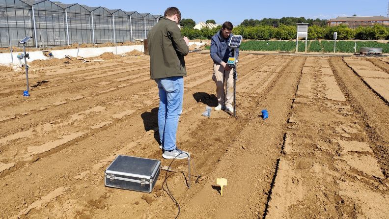 Dos personas midiendo el suelo en un campo agrícola.