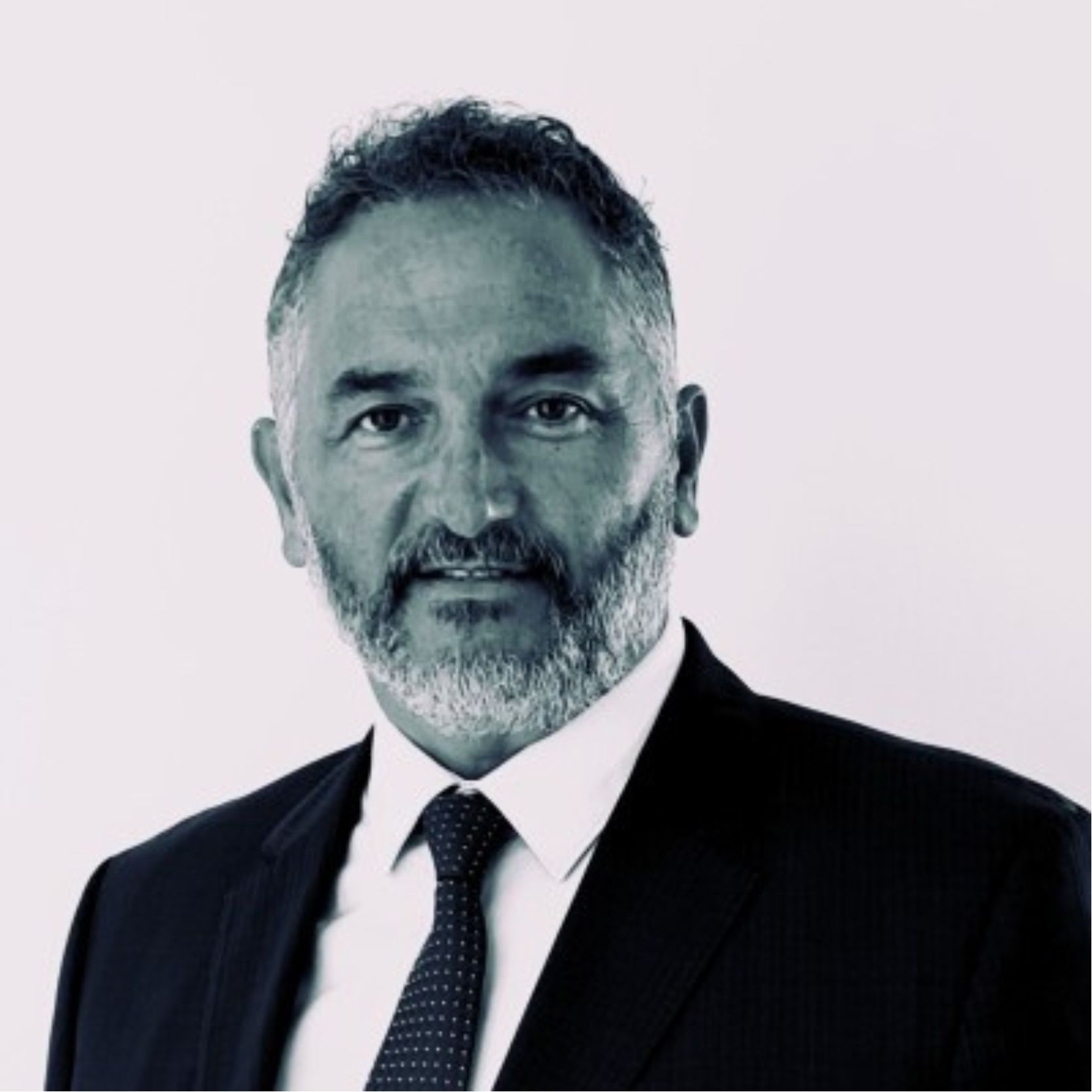Jorge Bártulos, fotografía en blanco y negro, con traje oscuro, camisa blanca y corbata, barba y expresión serena, fondo neutro claro.
