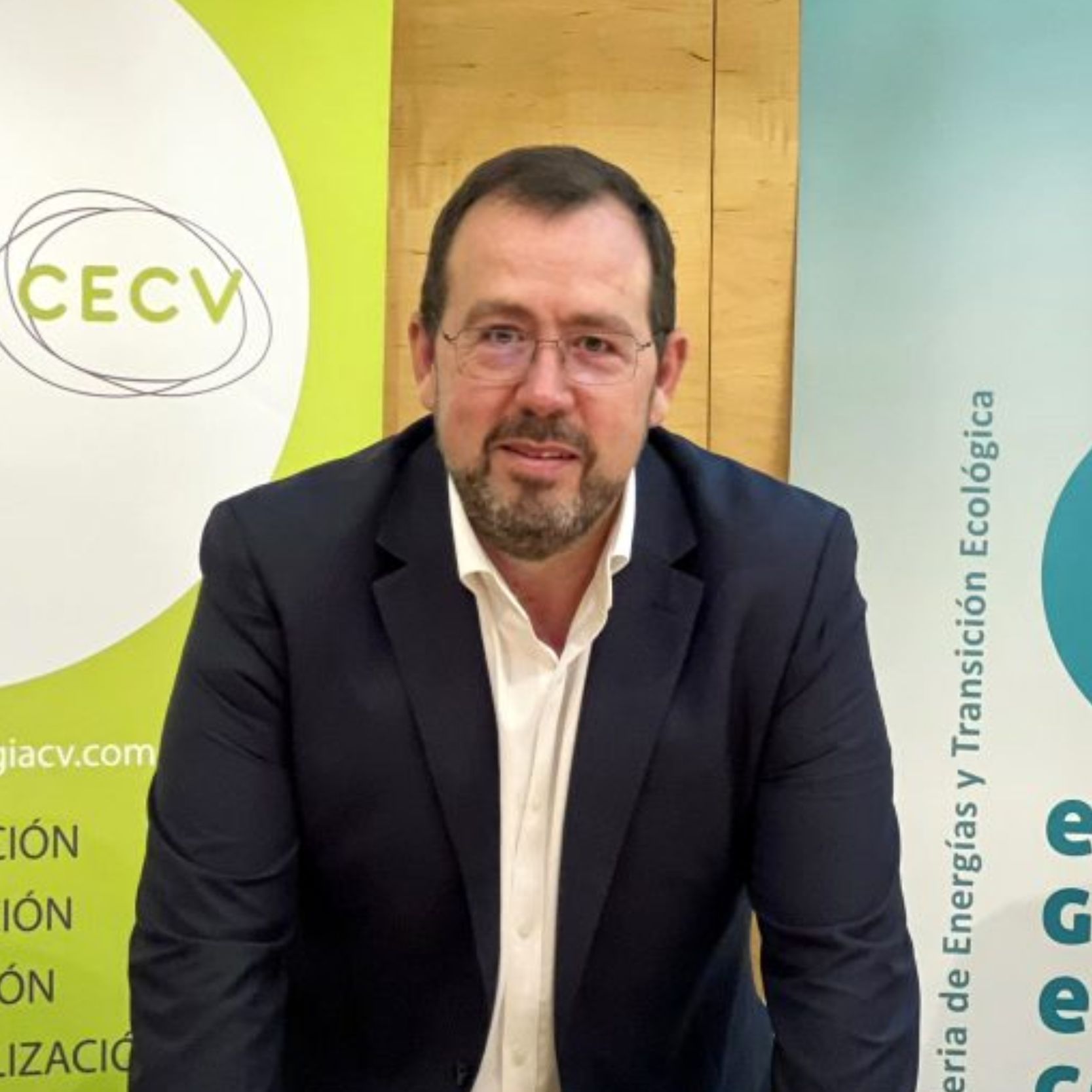 Ricardo Romaguera Faura, CEO de Inderen, con chaqueta azul marino y camisa blanca, gafas y barba, ante roll-ups de CECV y Conselleria de Energías.