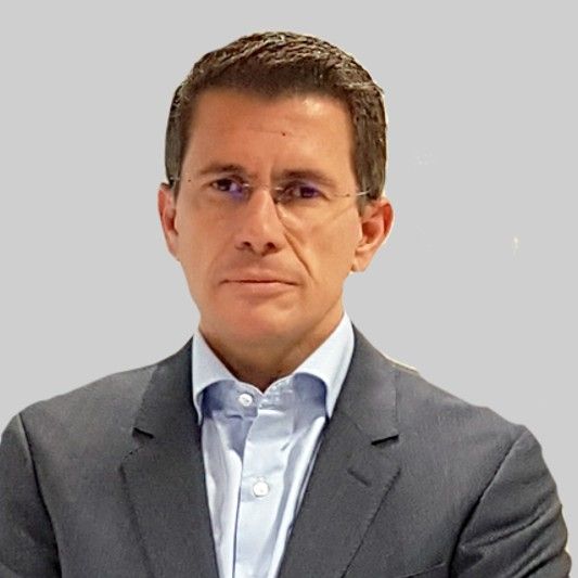 Hombre con traje gris y camisa azul claro.