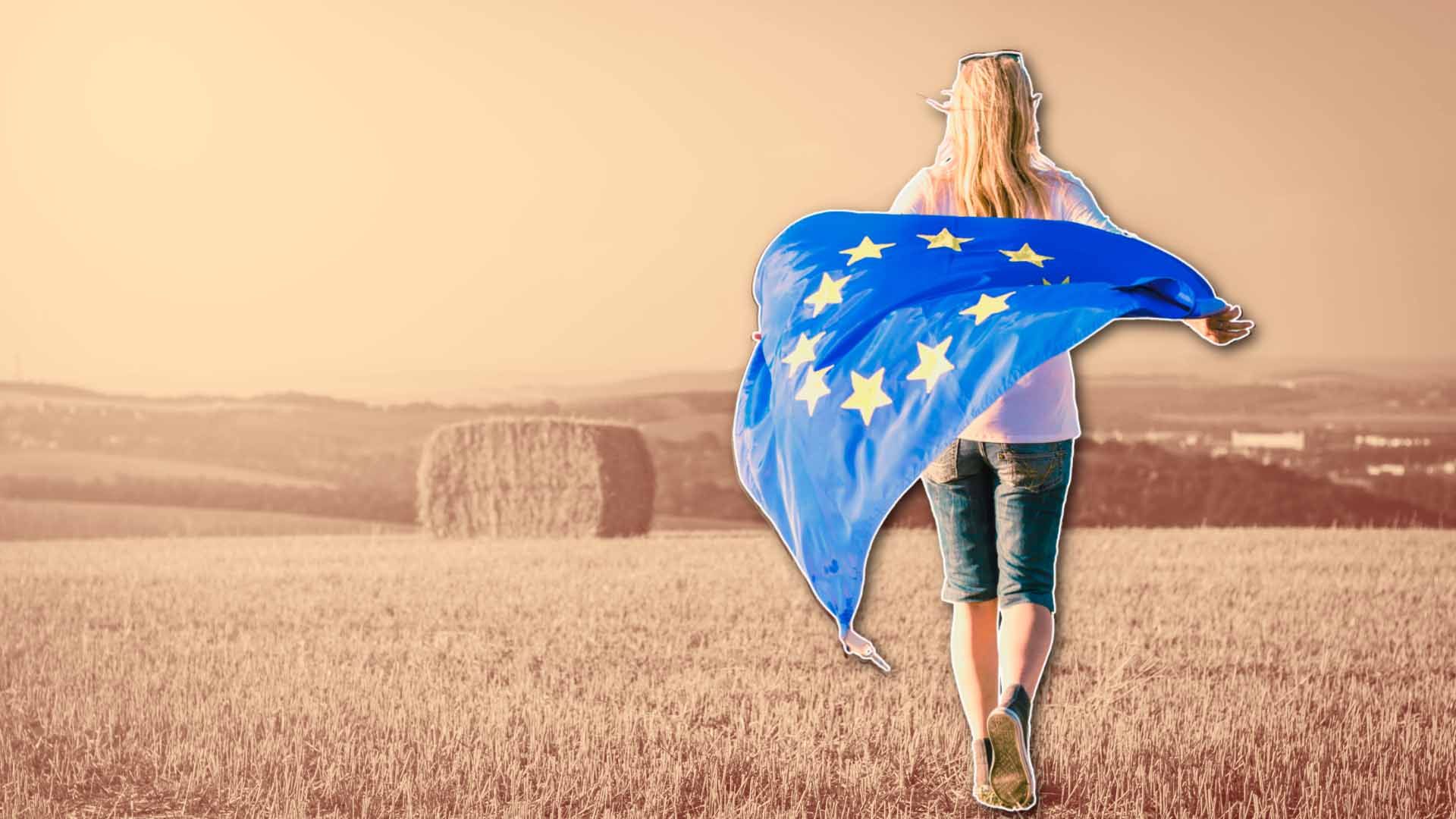 Mujer caminando con la bandera de la UE en un campo de cereal