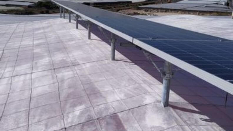Detalle de una línea de placas solares sobre un invernadero