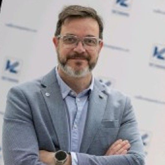 Hombre de negocios con traje gris y gafas cruzado de brazos.