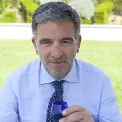 Un hombre con traje y corbata sonriendo y sosteniendo un objeto. Un hombre con traje y corbata sonriendo y sosteniendo un objeto.