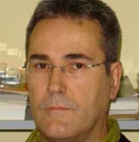Hombre con gafas y cabello corto en un entorno de oficina.