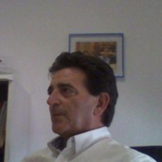 Hombre de cabello oscuro en camisa blanca mirando a la distancia.