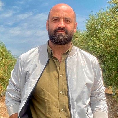 La imagen muestra a un hombre con chaqueta plateada y camisa verde. La imagen muestra a un hombre con chaqueta plateada y camisa verde.