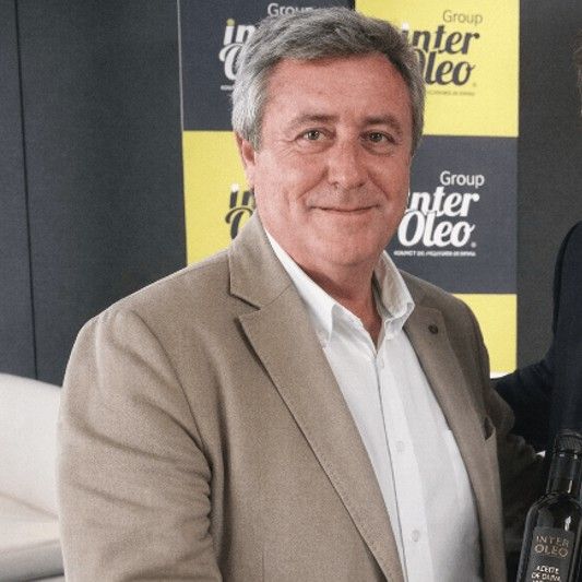 El hombre sonríe a la cámara con un botella de aceite de oliva. El hombre sonríe a la cámara con un botella de aceite de oliva.