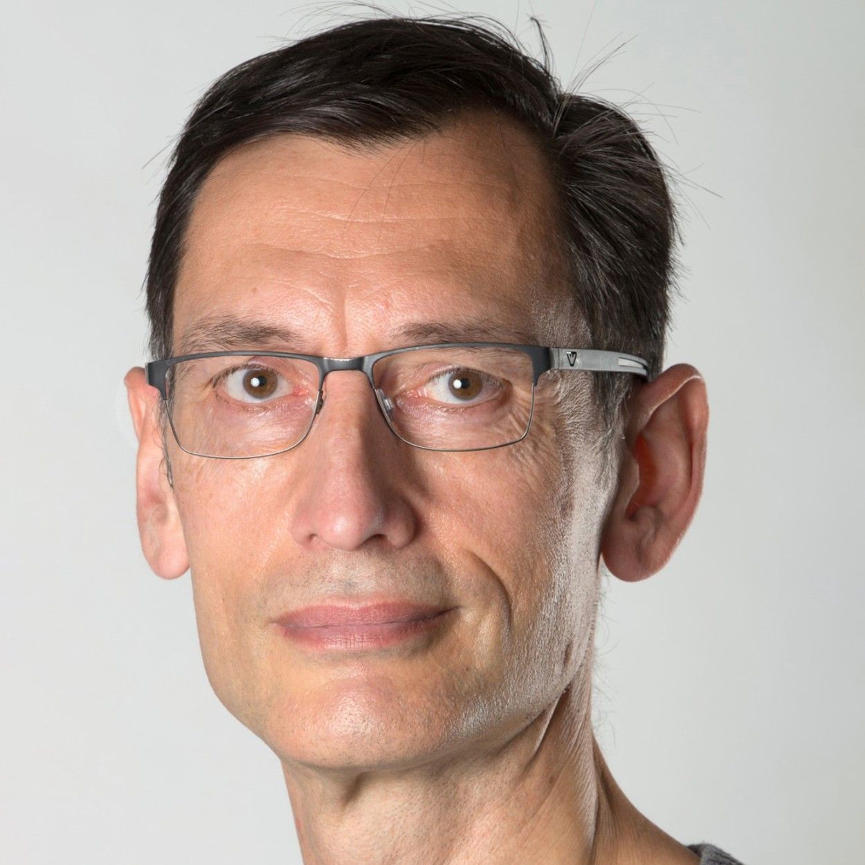 Hombre con gafas y cabello oscuro mirando a la cámara.
