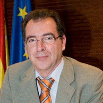Hombre con gafas y corbata en un entorno oficial.