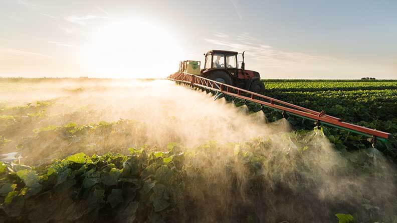  Granjero en un tractor con un rociador de fertilizantes y bioestimulantes