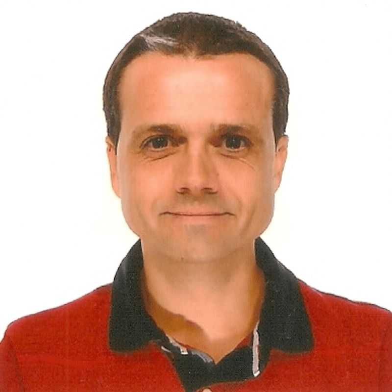 Hombre con camisa roja y polo negro, fondo blanco.
