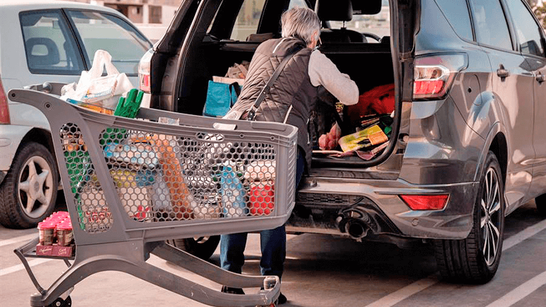 Una mujer carga su vehículo con la compra