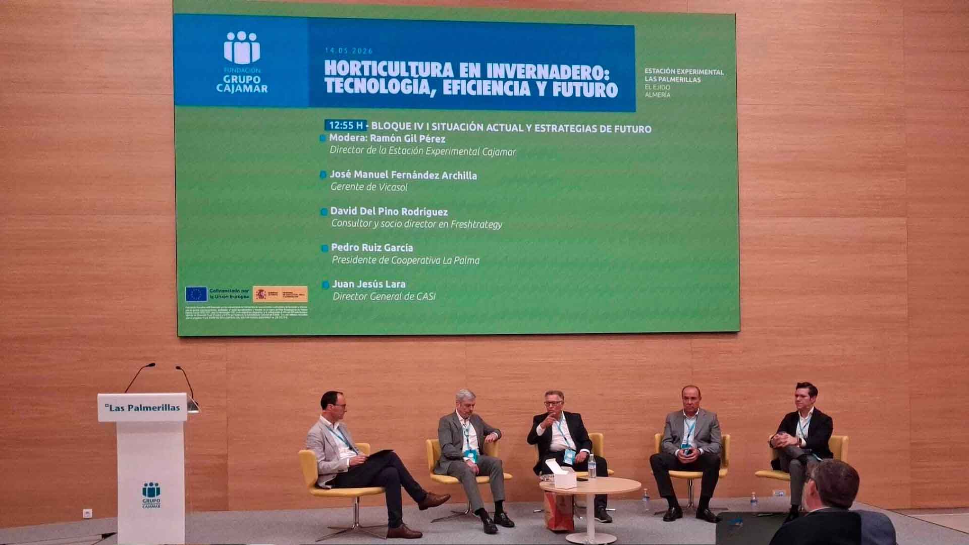 Cinco hombres en traje sentados en sillas en una conferencia sobre horticultura en invernadero.