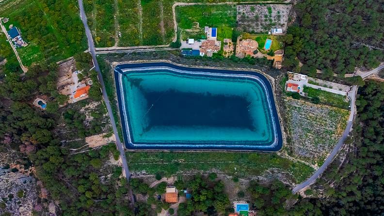 Vista aérea de una piscina de forma rectangular en medio de un paisaje natural.
