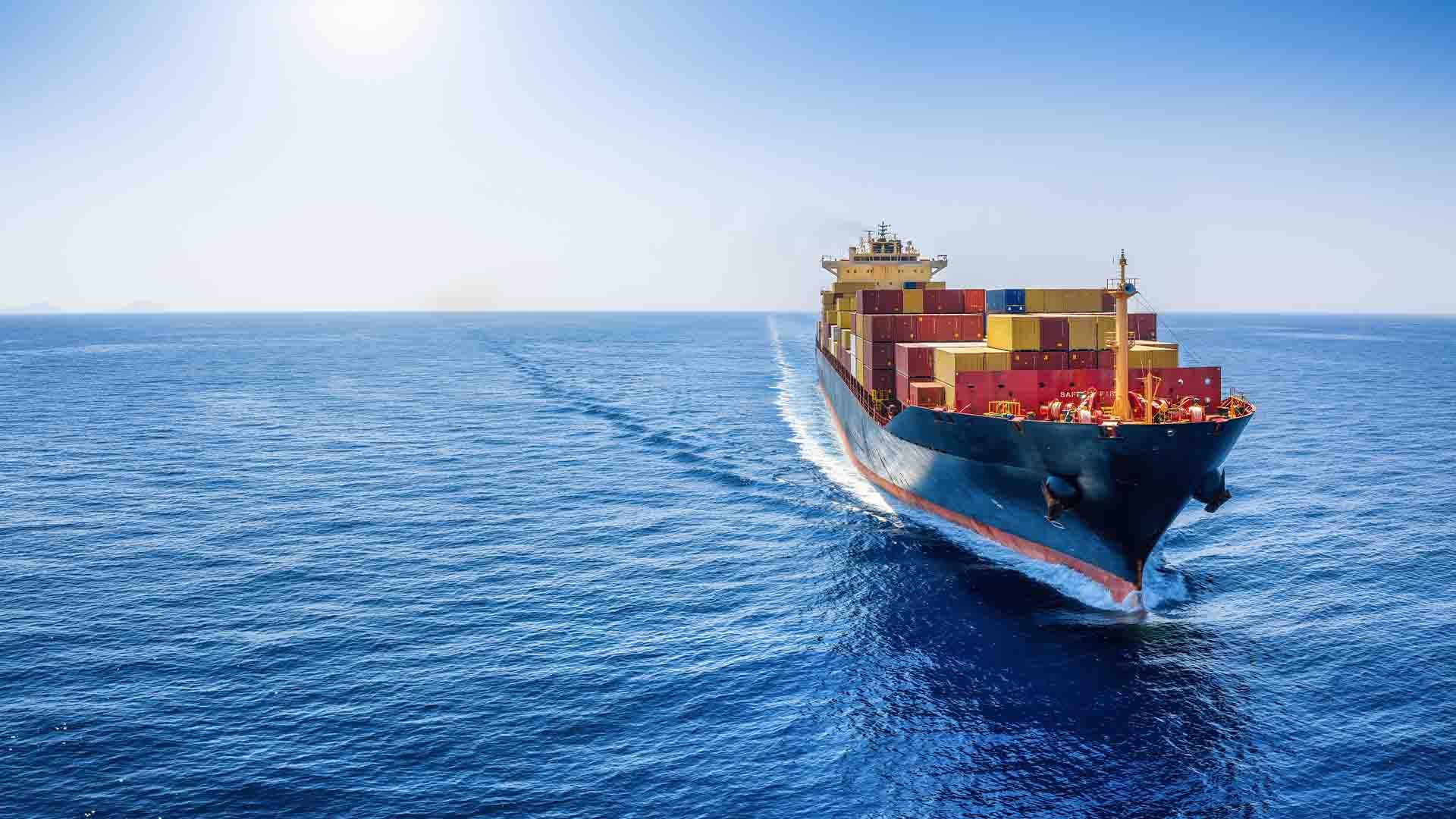 Barco de carga con contenedores en medio del mar en un día soleado.