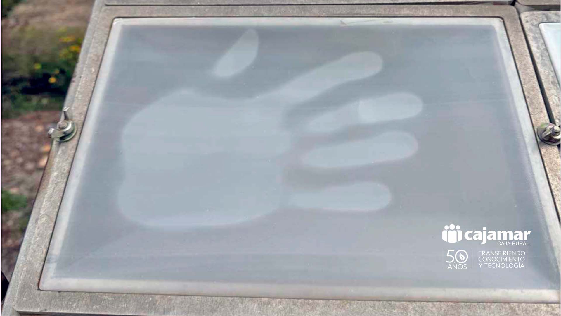 Huella de mano visible en panel exterior con logo de Cajamar.