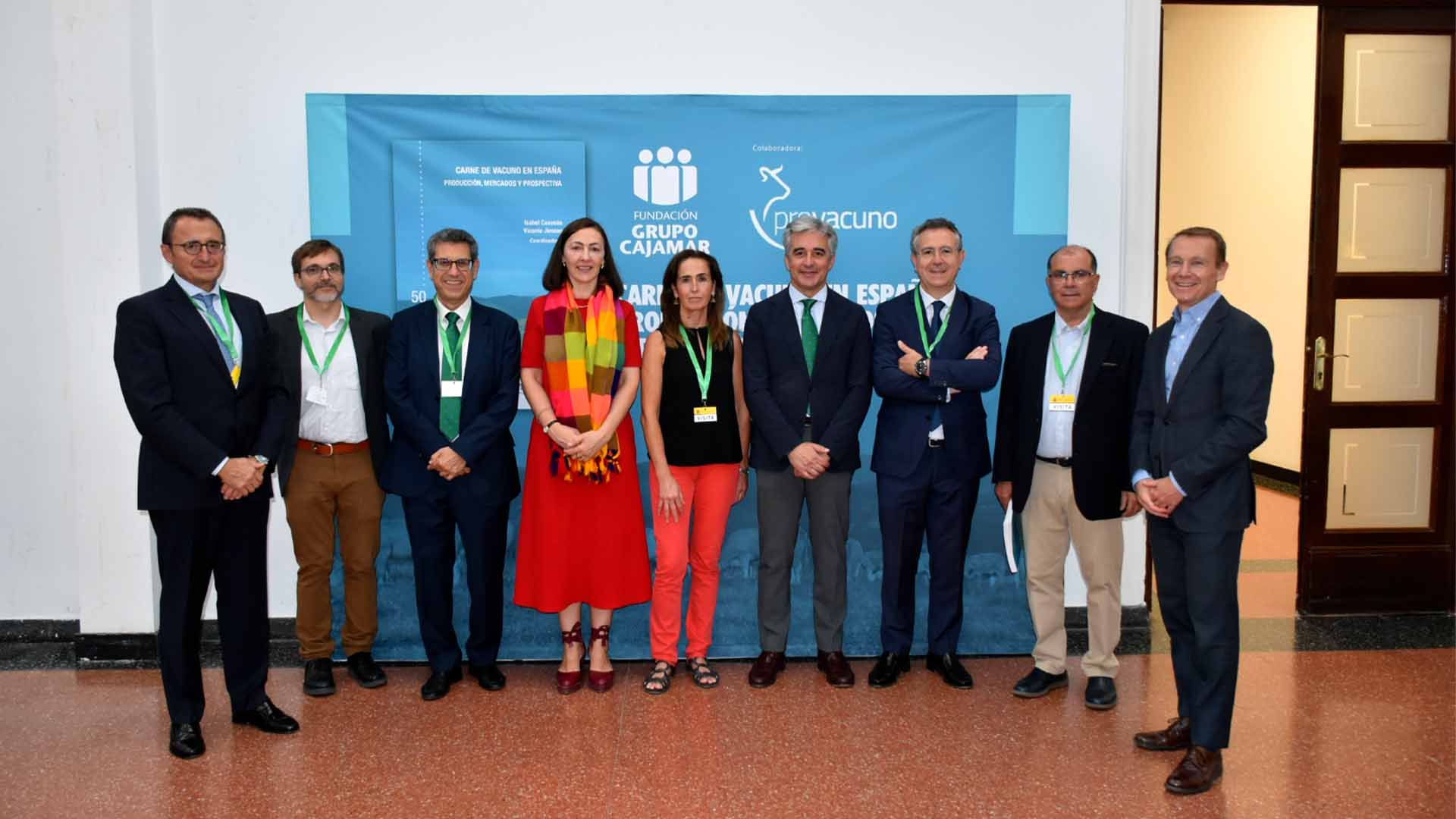 Grupo de personas vestidas de manera formal posando ante un cartel relacionado con ganado.