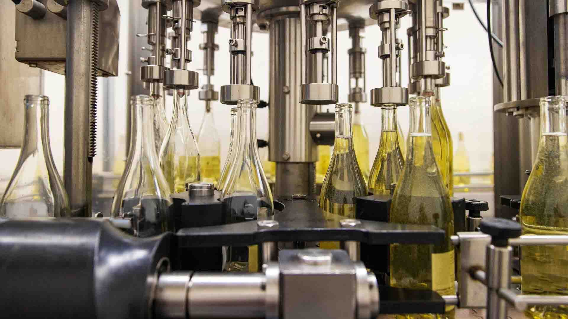 Máquina de embotellado en fábrica con botellas de vidrio.