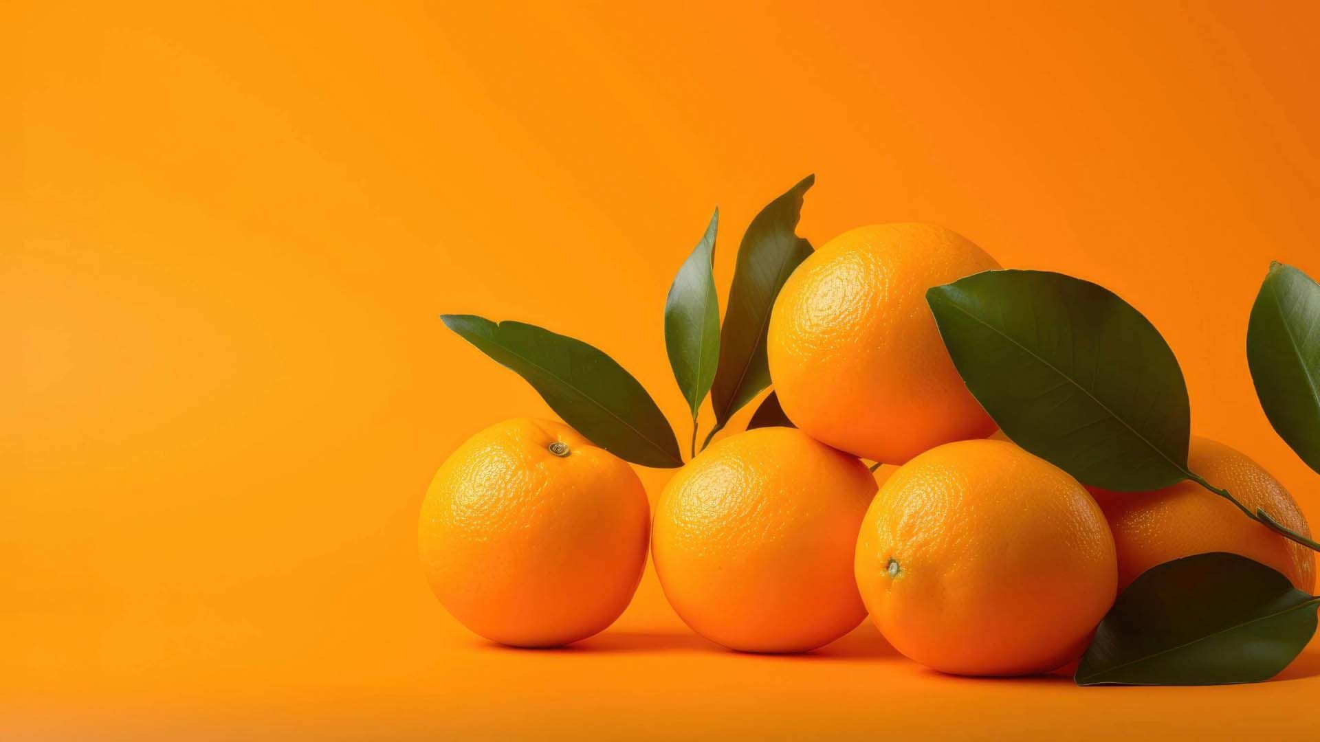 Naranjas frescas con hojas verdes sobre fondo naranja.
