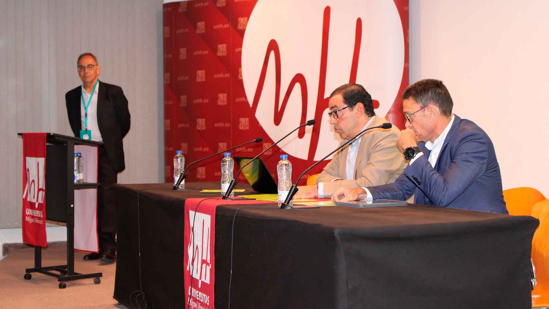 Panel de discusión en un evento universitario con tres hombres.