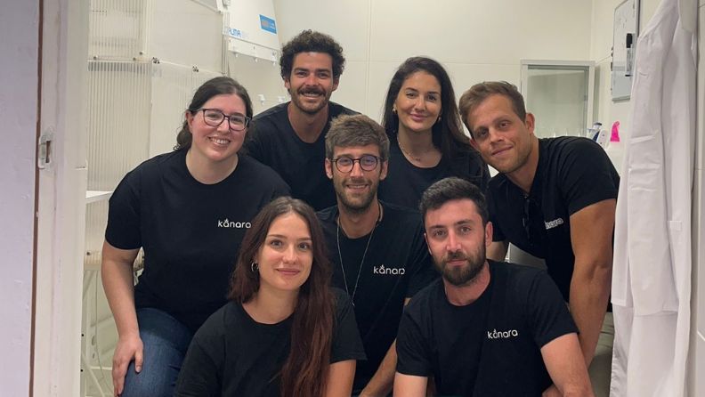 Grupo de siete personas sonriendo en un pasillo, con ropa negra.