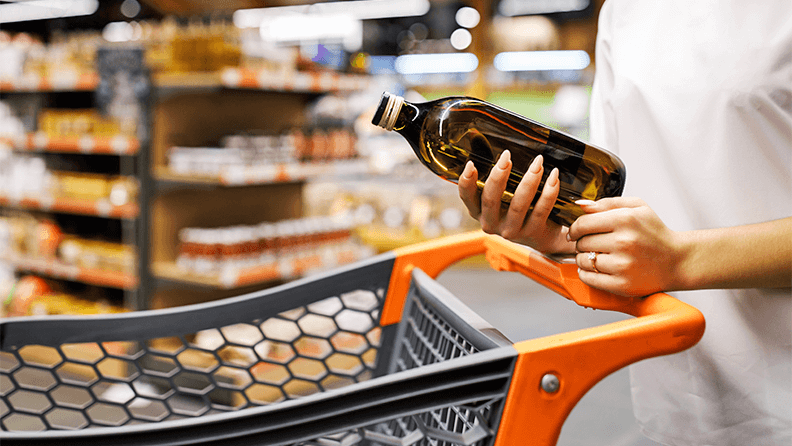 Una mujer sostiene una botella de aceite de oliva en el supermercado