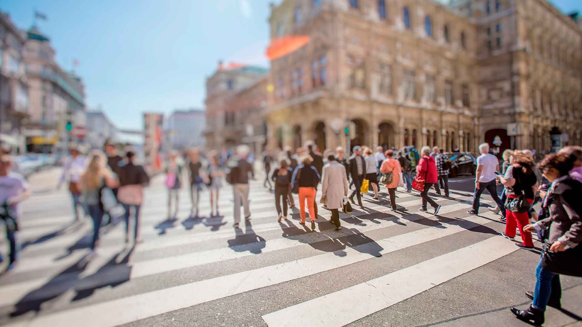 Multitud de personas cruzando la calle en paso de peatones en zona urbana.