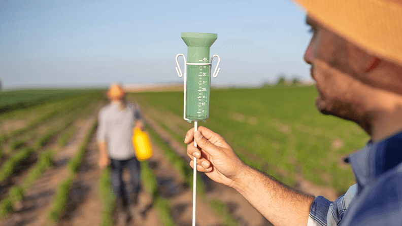 Un joven agrónomo sosteniendo un pluviómetro