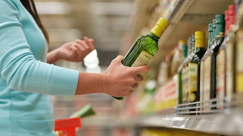 Una mujer sostiene una botella de aceite de oliva en un supermercado