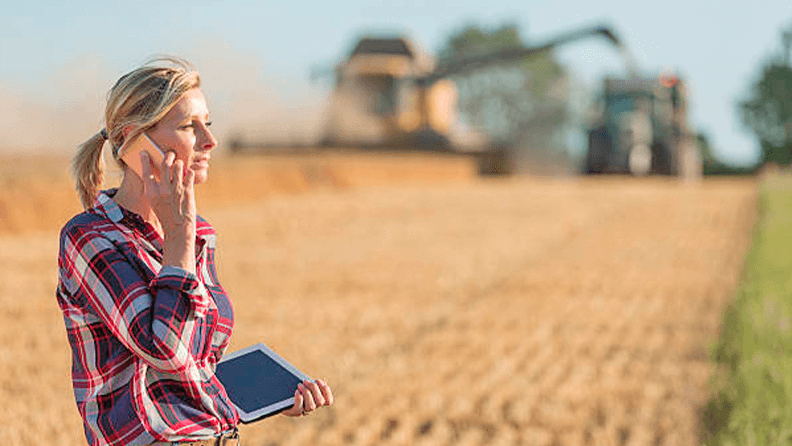Mujer con dispositivos digitales en un campo sembrado