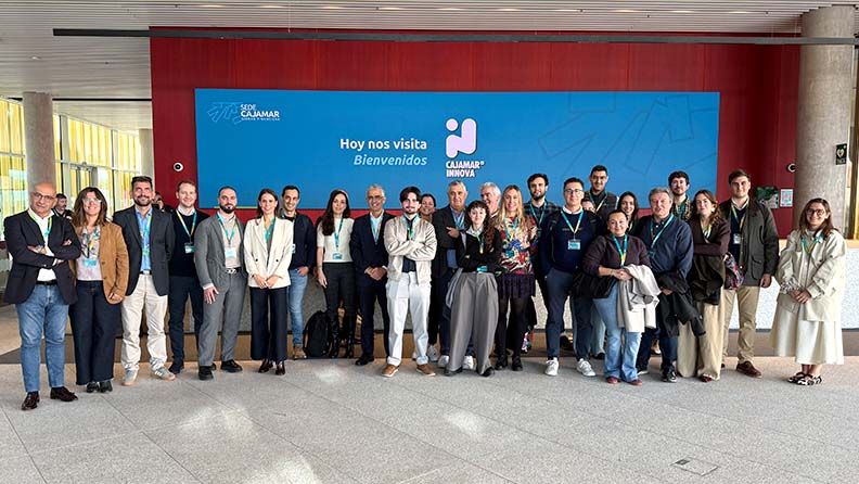 Un grupo de personas sonriendo para una foto en un espacio con piso de baldosas grises.