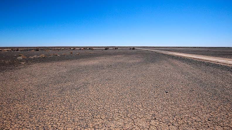 Paisaje árido con camino de tierra y cielo azul.