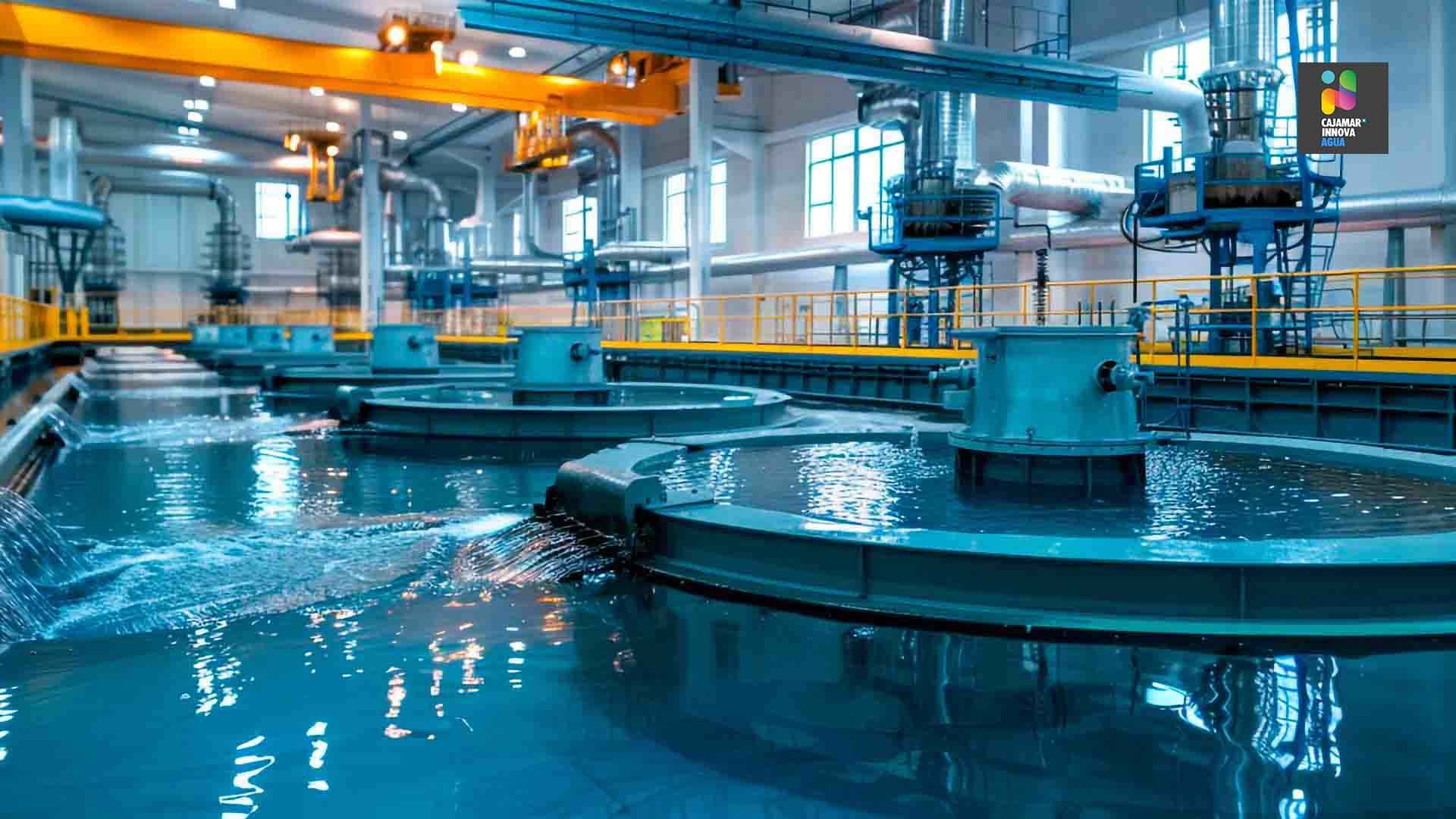 Planta de tratamiento de agua con grandes depósitos circulares y líquido azul fluyendo.